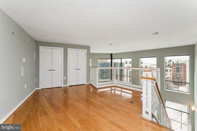 interior space with baseboards, wood finished floors, and a healthy amount of sunlight