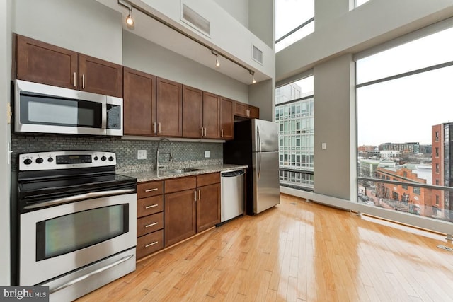 kitchen with appliances with stainless steel finishes, a city view, a sink, and a towering ceiling