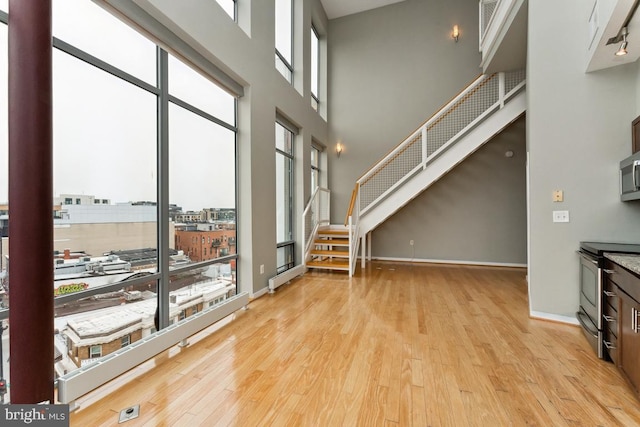 living room featuring baseboards, stairway, and light wood finished floors