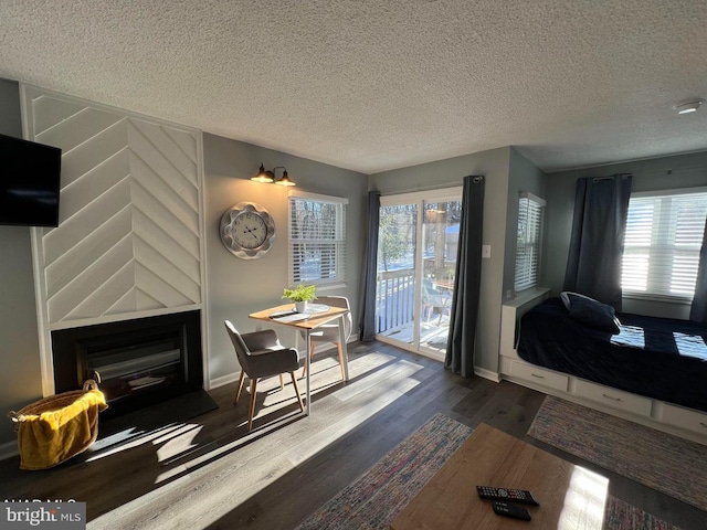 dining area with a textured ceiling, wood finished floors, plenty of natural light, and a glass covered fireplace