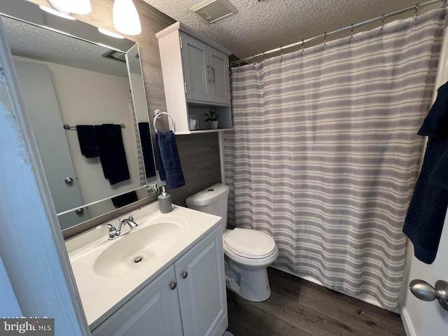 full bath with a textured ceiling, toilet, wood finished floors, visible vents, and vanity