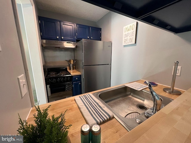 kitchen with black gas range oven, butcher block counters, freestanding refrigerator, blue cabinets, and under cabinet range hood