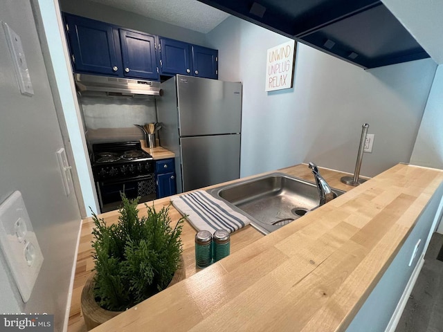 kitchen featuring blue cabinetry, freestanding refrigerator, a sink, black range, and under cabinet range hood