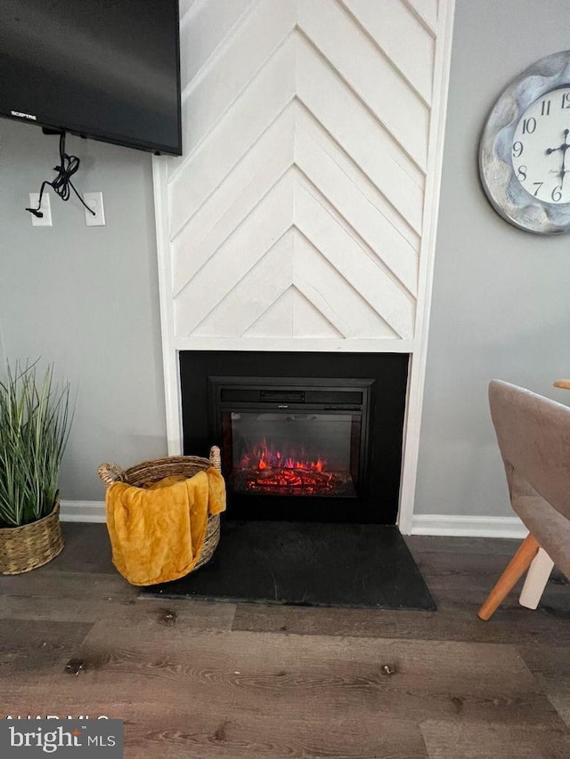 room details featuring baseboards, wood finished floors, and a glass covered fireplace