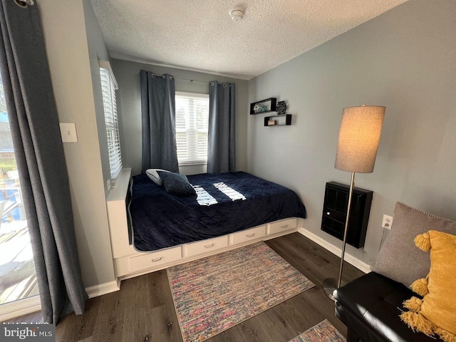 bedroom featuring a textured ceiling, baseboards, and dark wood-style flooring