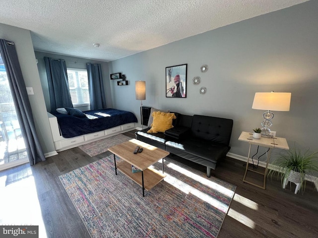 living area with dark wood-style floors, baseboards, and a textured ceiling