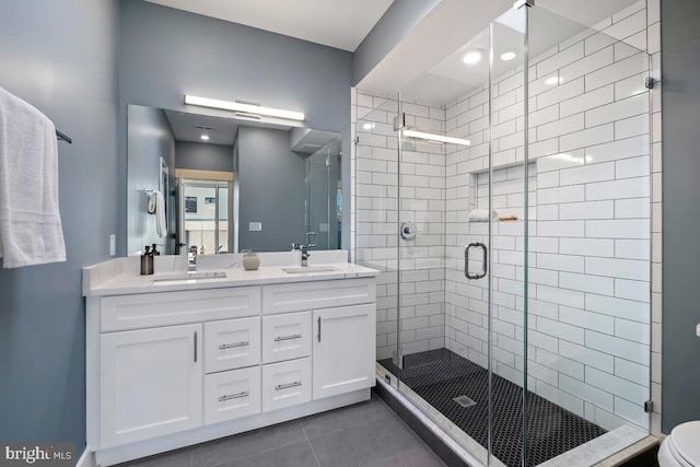 bathroom with double vanity, a stall shower, tile patterned flooring, and a sink