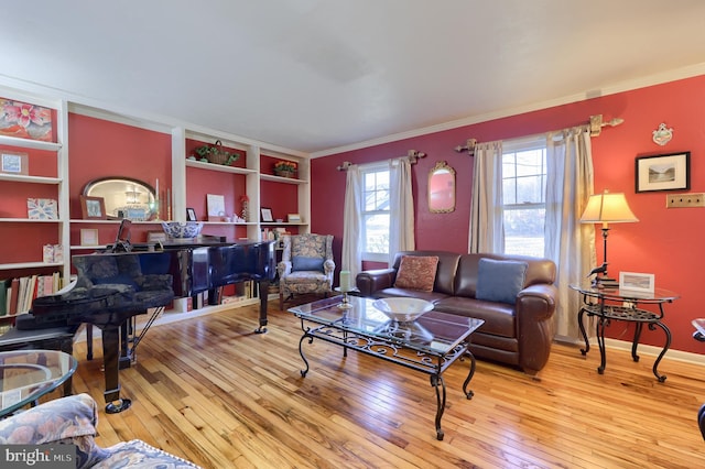 living area with ornamental molding, light wood-type flooring, and baseboards