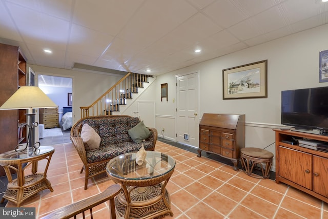 living area with recessed lighting, a paneled ceiling, stairway, and tile patterned floors