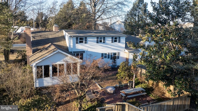 rear view of property featuring roof with shingles and a chimney