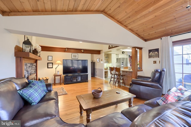 living room featuring high vaulted ceiling, a stone fireplace, light wood-type flooring, and wood ceiling