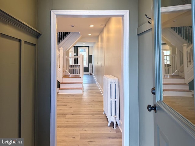 hallway featuring radiator, light wood-type flooring, stairway, and recessed lighting