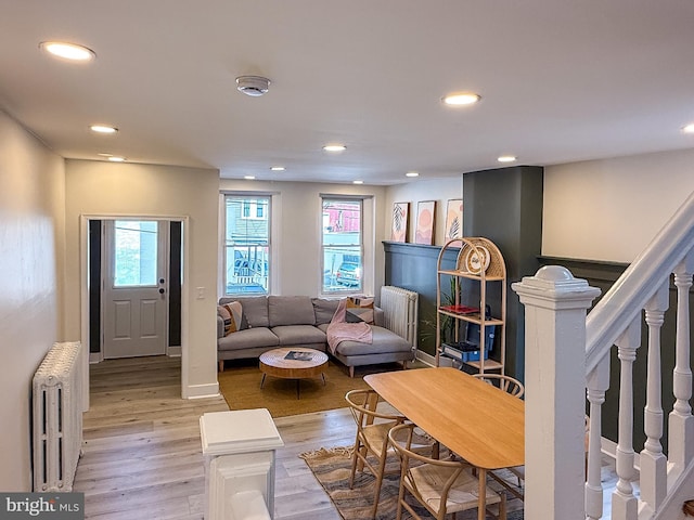 living area with recessed lighting, radiator, light wood-style flooring, and stairs