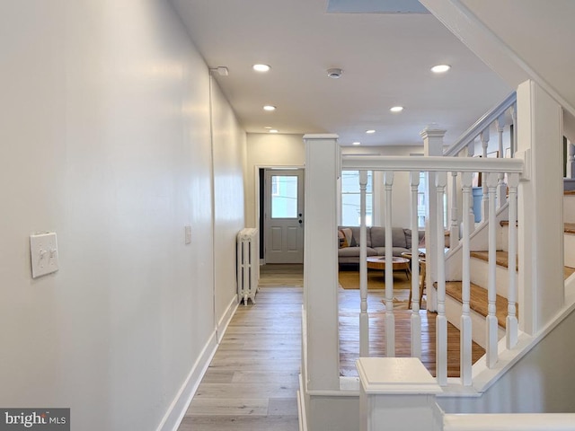 hall with light wood-style floors, radiator heating unit, stairs, and recessed lighting