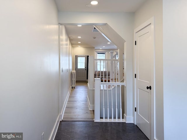 corridor with dark wood-type flooring, recessed lighting, baseboards, and radiator heating unit