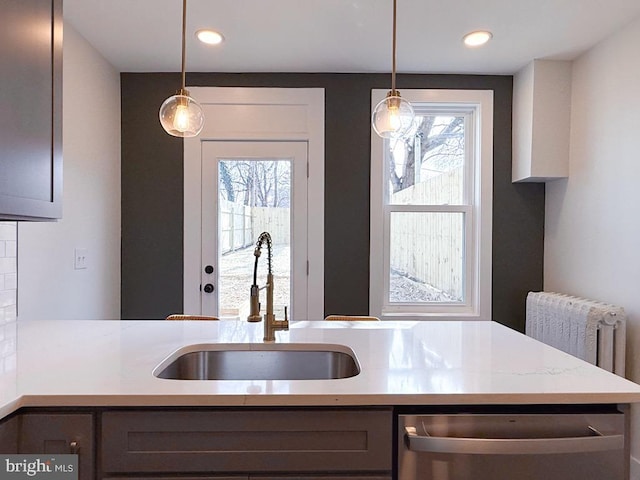 kitchen featuring pendant lighting, recessed lighting, radiator, light countertops, and a sink