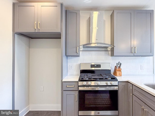 kitchen with stainless steel range with gas cooktop, tasteful backsplash, gray cabinets, light countertops, and wall chimney exhaust hood