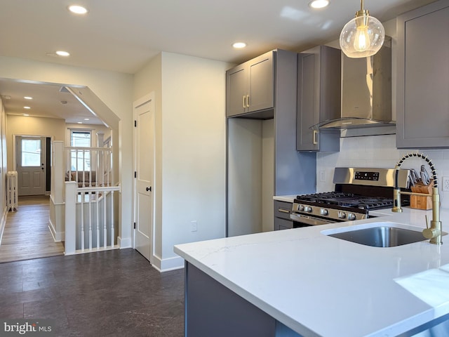 kitchen with tasteful backsplash, wall chimney exhaust hood, gray cabinets, stainless steel range with gas stovetop, and recessed lighting