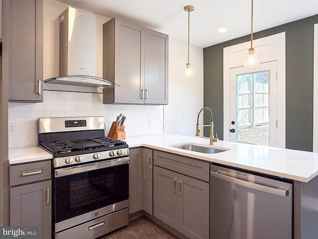 kitchen featuring appliances with stainless steel finishes, a sink, wall chimney range hood, and gray cabinetry