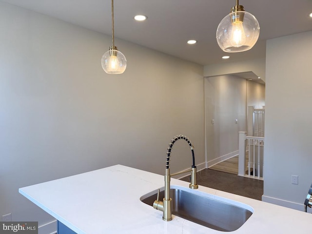 kitchen featuring hanging light fixtures, a sink, light countertops, and recessed lighting