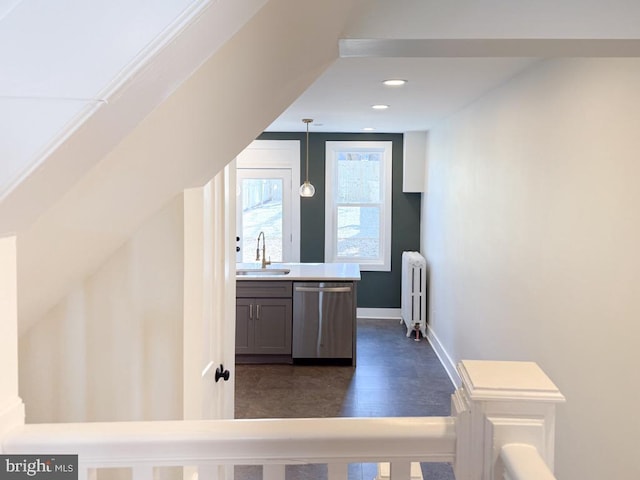 bar with a sink, baseboards, radiator, dishwasher, and dark wood finished floors