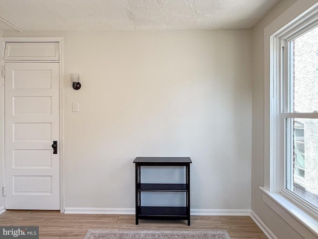 spare room featuring a textured ceiling, baseboards, and wood finished floors