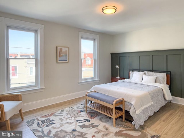 bedroom featuring light wood-type flooring, multiple windows, and baseboards