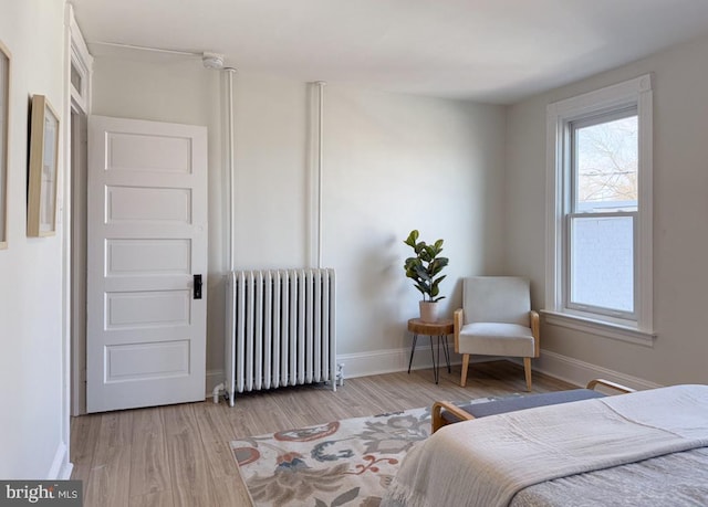 bedroom featuring radiator, baseboards, and wood finished floors