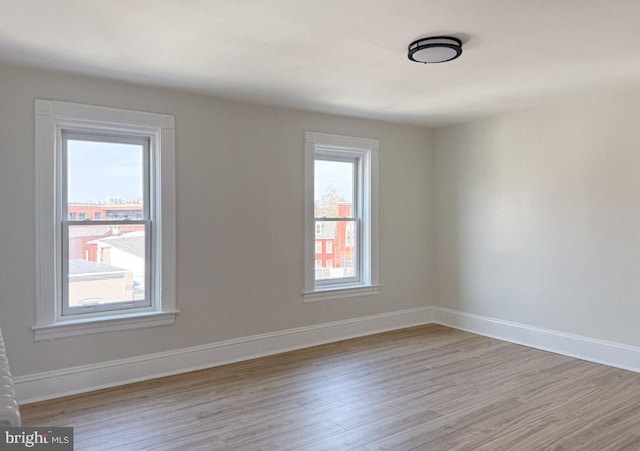 unfurnished room with light wood-style flooring and baseboards