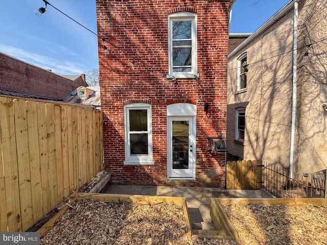 exterior space featuring brick siding and fence