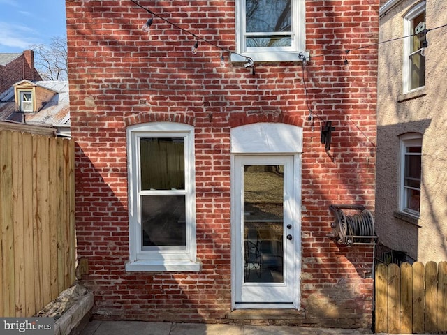 entrance to property with fence and brick siding