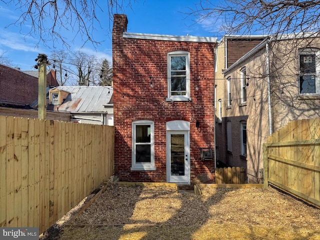 back of house featuring fence and brick siding