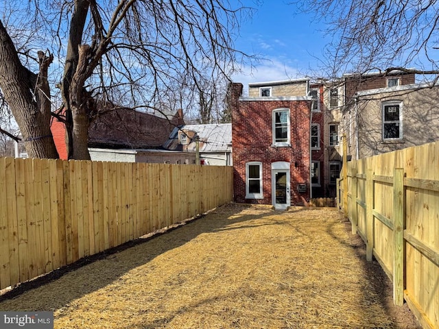 rear view of property featuring brick siding and a fenced backyard