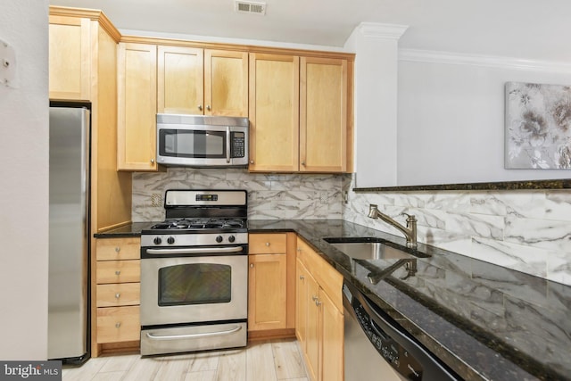 kitchen featuring backsplash, appliances with stainless steel finishes, ornamental molding, a sink, and dark stone counters