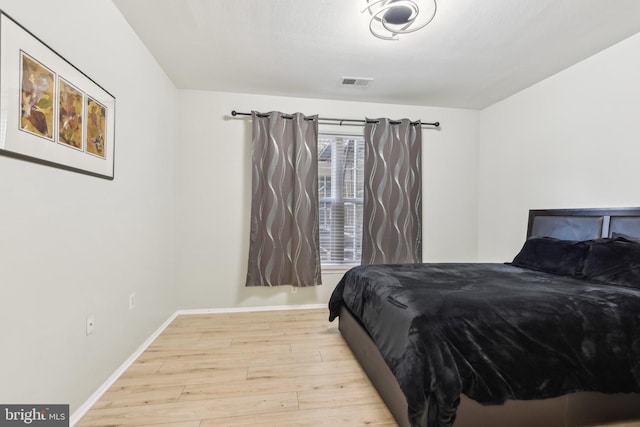 bedroom with light wood-type flooring, baseboards, and visible vents