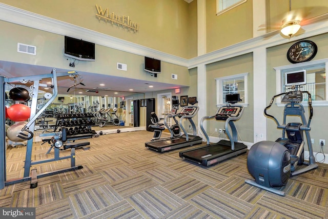 workout area with a towering ceiling, visible vents, and carpet flooring