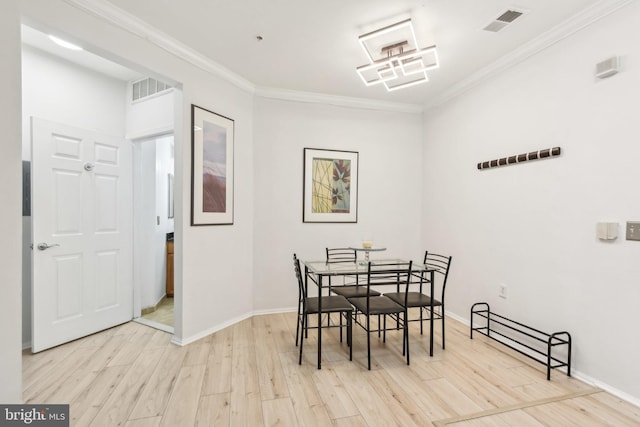 dining area with light wood-style floors, baseboards, visible vents, and crown molding