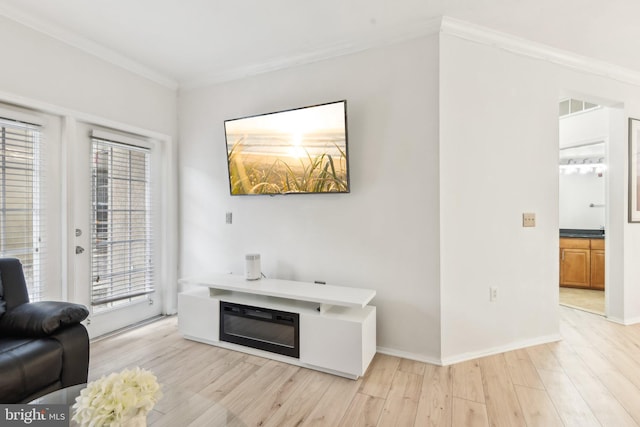 living room featuring light wood-style flooring, visible vents, baseboards, and ornamental molding