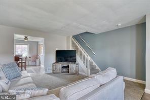 living area with baseboards and stairs