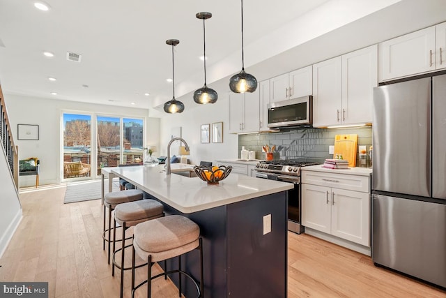 1605 Holbrook NE Unit 4, Washington, DC 20002 - kitchen featuring white cabinets, appliances with stainless steel finishes, decorative light fixtures, a kitchen island with sink, and light countertops