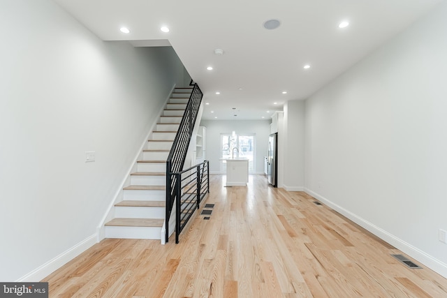 stairway featuring baseboards, visible vents, wood finished floors, and recessed lighting