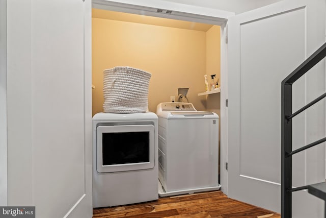 laundry area featuring laundry area, wood finished floors, and washing machine and clothes dryer