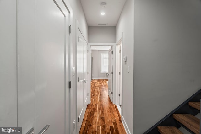 hall featuring baseboards, visible vents, wood finished floors, stairs, and recessed lighting