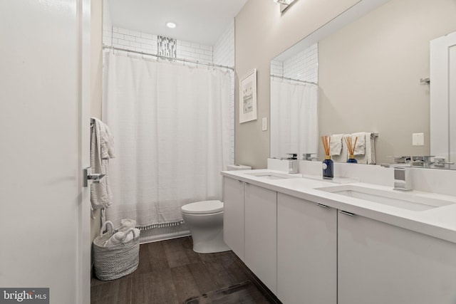 full bathroom featuring double vanity, a sink, toilet, and wood finished floors