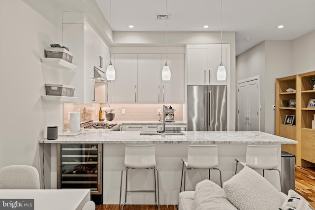 kitchen with wine cooler, high end refrigerator, wood finished floors, a kitchen breakfast bar, and decorative backsplash