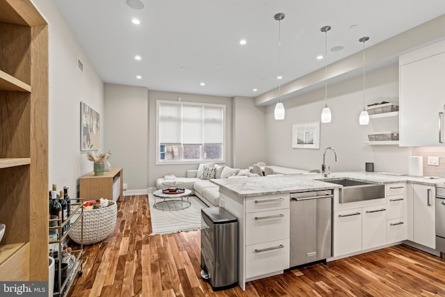 kitchen with white cabinets, dishwasher, a peninsula, light stone countertops, and a sink