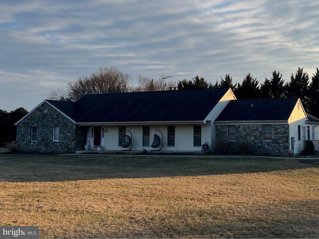 ranch-style house with a front yard and stone siding