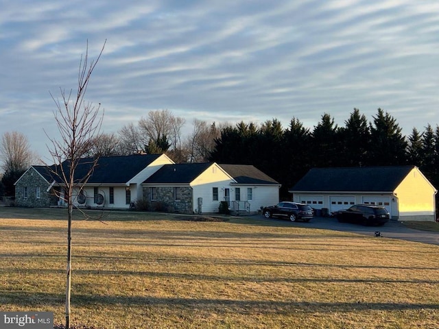 view of front facade featuring a front yard, an outdoor structure, and a detached garage