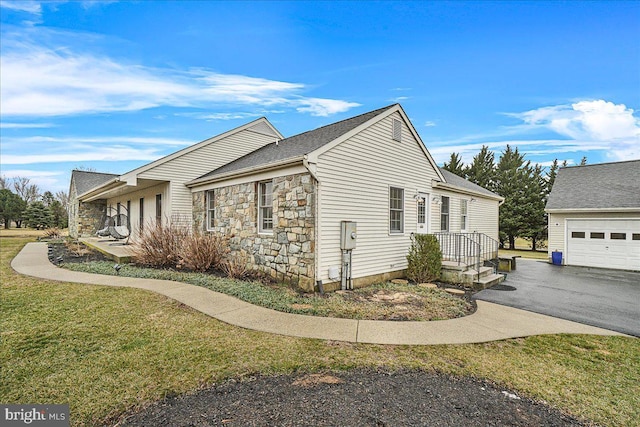 view of property exterior with driveway, stone siding, a garage, and a yard