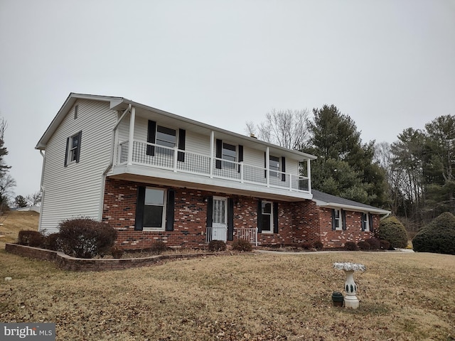 view of front of home featuring a front yard, brick siding, and a balcony